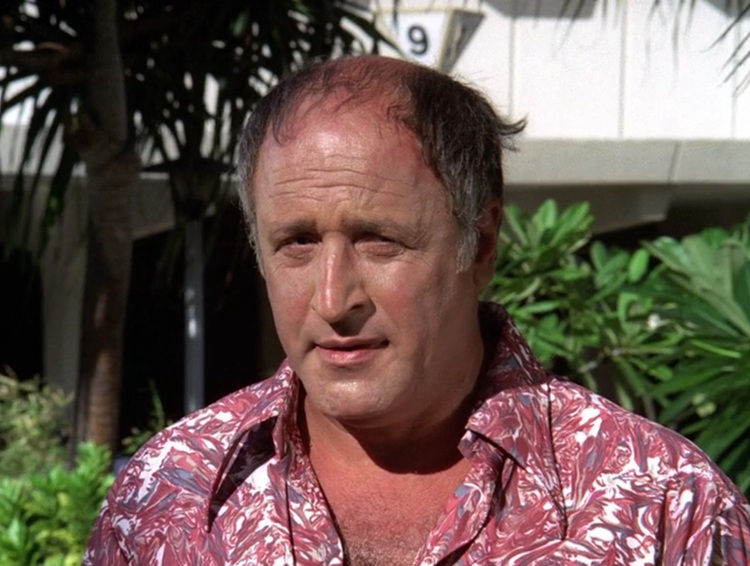 Vic Tayback, a balding middle-aged white man wearing a burgundy and white Aloha shirt.