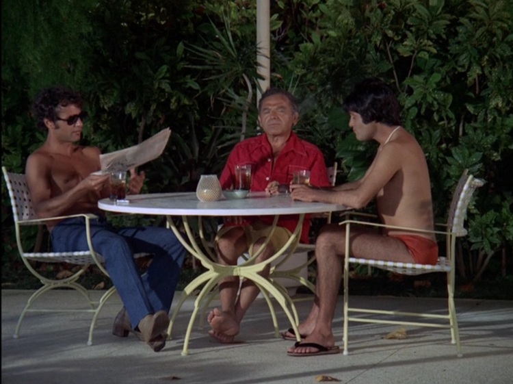 Sal Mineo as Eddie, a younger tanned white man with curly dark hair, shirtless, wearing sunglasses and jeans, Nehemiah Persoff as Cordell, a middle aged white man with short dark hair wearing a red button down shirt, and Tommy Sands as Joey Hall, a young tanned white man with longer dark hair and wearing red booty swim trunks. They're sitting at a table poolside.